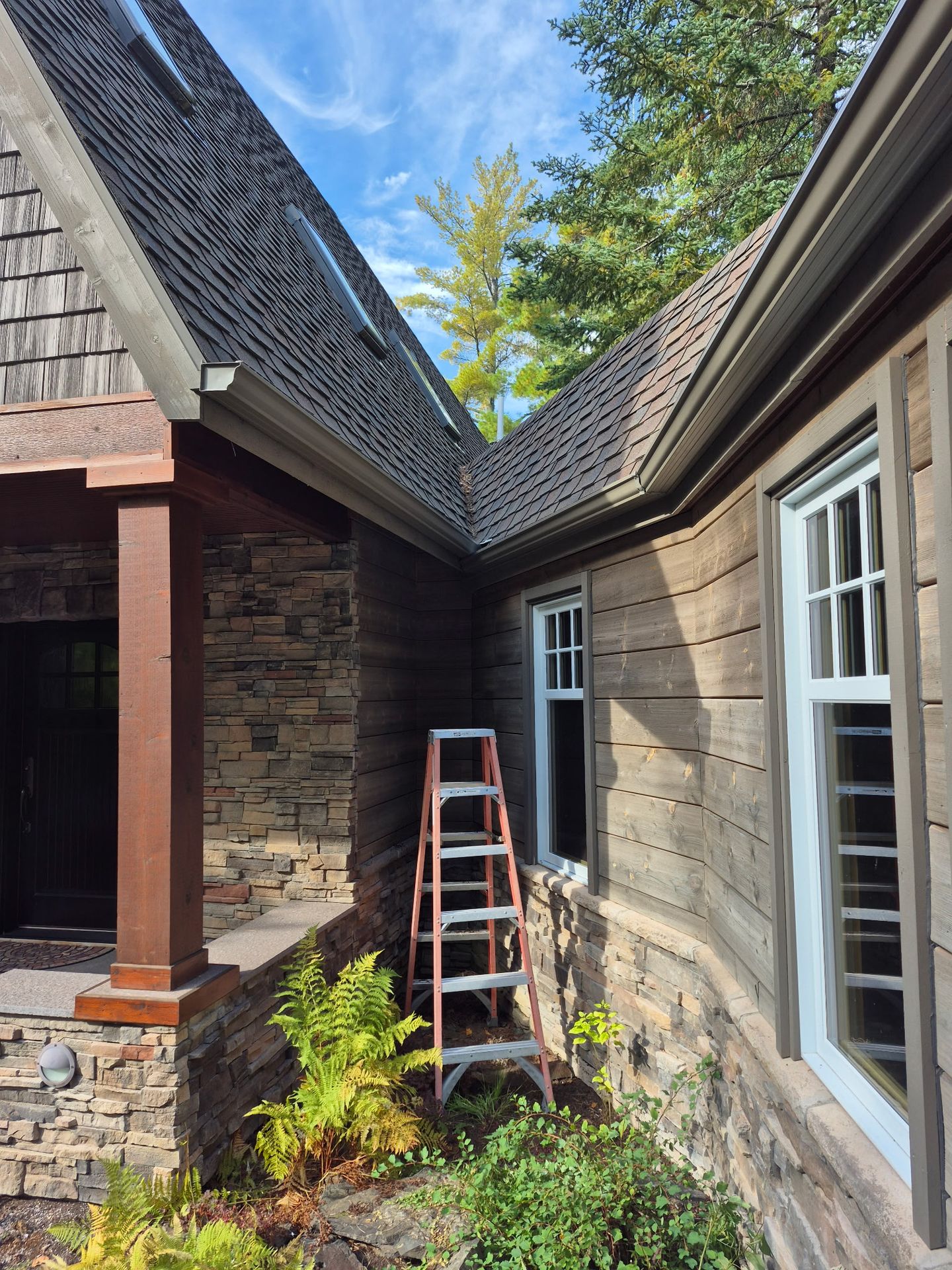 Custom gutter installation on brick house with complex roofline in International Falls